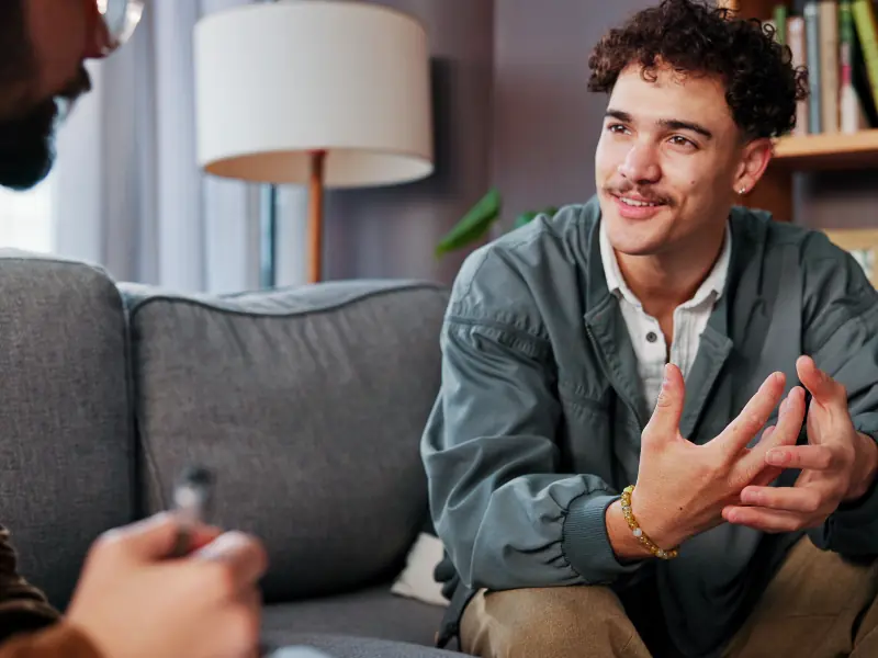 Psychology, therapist and happy man talking for help, mental health advice or support in office.